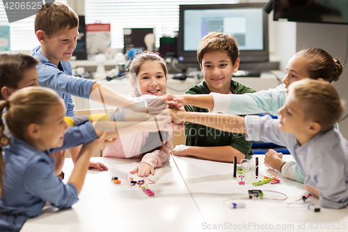 Image of happy children holding hands at robotics school