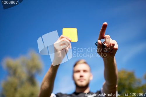 Image of referee on football field showing yellow card