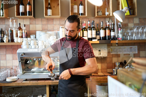 Image of barista with holder and tamper making at coffee
