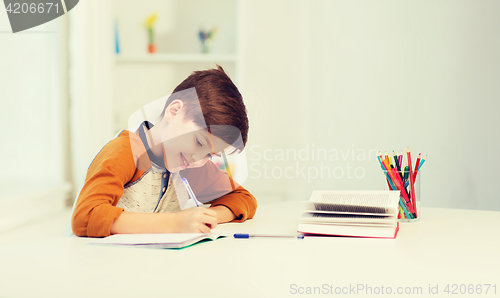 Image of smiling student boy writing to notebook at home