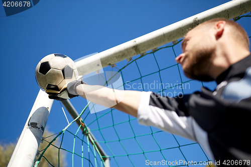 Image of goalkeeper with ball at football goal on field