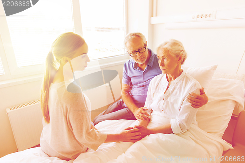 Image of family visiting ill senior woman at hospital