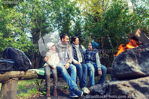 Image of happy family sitting on bench at camp fire