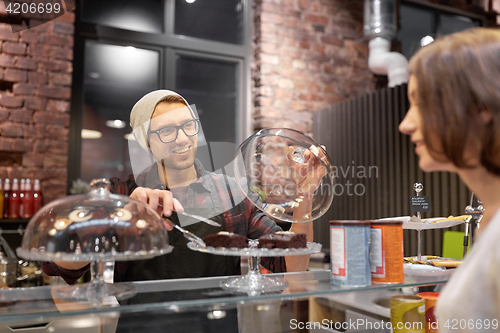 Image of man or barman with cakes serving customer at cafe