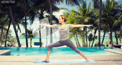 Image of woman making yoga warrior pose over hotel resort