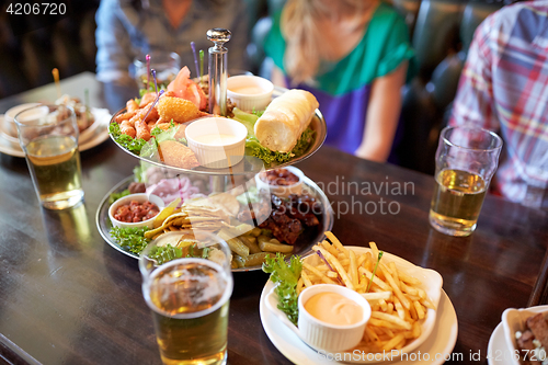 Image of people sitting at table with food and beer at bar