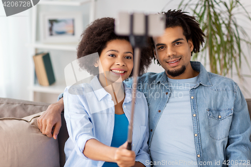 Image of happy couple with smartphone taking selfie at home