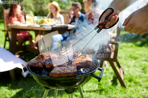 Image of man cooking meat on barbecue grill at summer party