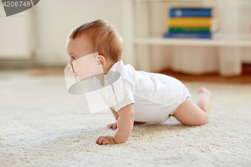 Image of little baby in diaper crawling on floor at home