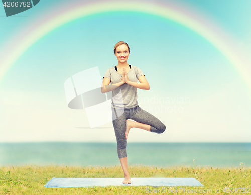 Image of woman making yoga in tree pose on mat