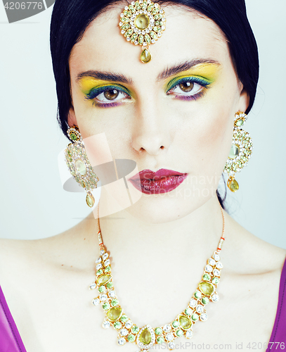 Image of young pretty caucasian woman like indian in ethnic jewelry close up on white, bridal bright makeup