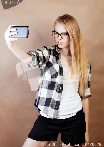 Image of young pretty blond hipster girl making selfie on warm brown background, lifestyle people concept