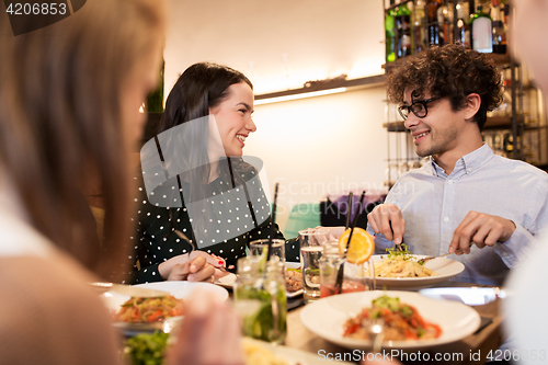 Image of happy friends eating and drinking at restaurant