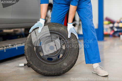 Image of mechanic with wheel tire at car workshop