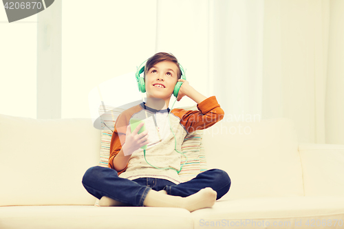 Image of happy boy with smartphone and headphones at home