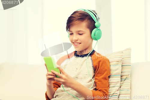 Image of happy boy with smartphone and headphones at home