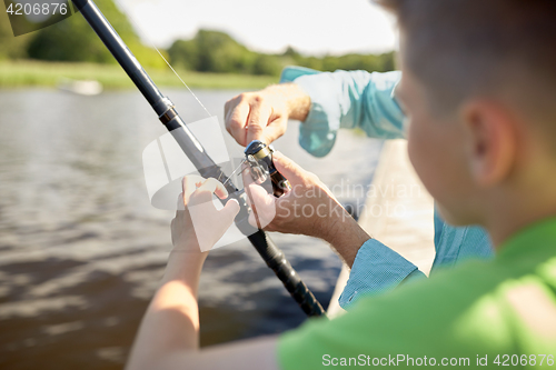 Image of boy and grandfather with fishing rod on river