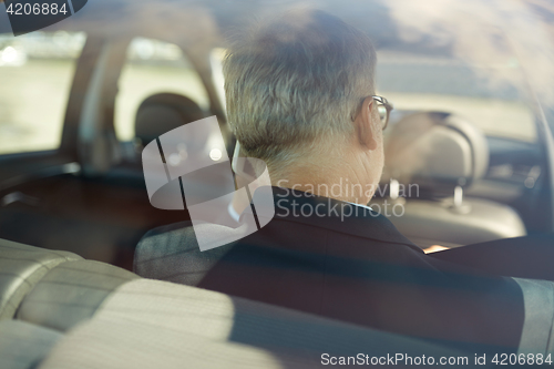 Image of senior businessman calling on smartphone in car