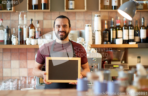 Image of happy man or waiter with chalkboard banner at bar
