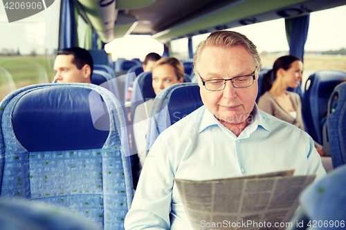 Image of happy senior man reading newspaper in travel bus
