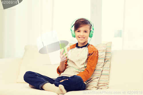 Image of happy boy with smartphone and headphones at home