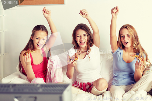 Image of happy friends or teen girls eating pizza at home