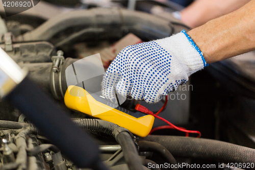 Image of auto mechanic man with multimeter testing battery