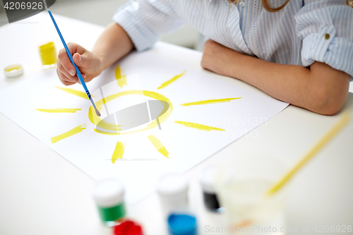 Image of girl with brush drawing sun on paper