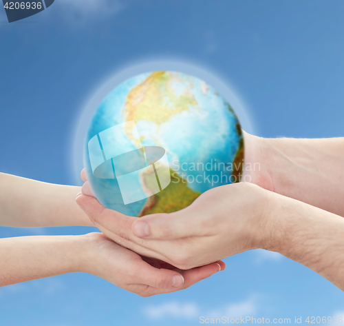 Image of child and father hands holding earth planet