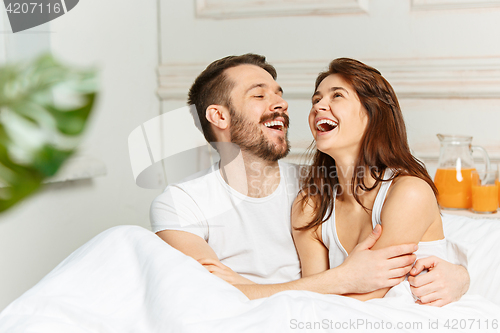 Image of Young adult heterosexual couple lying on bed in bedroom