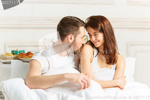 Image of Young adult heterosexual couple lying on bed in bedroom