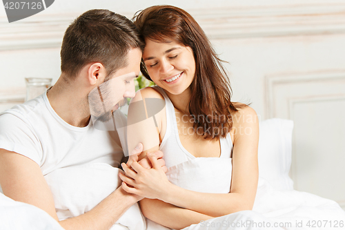 Image of Young adult heterosexual couple lying on bed in bedroom