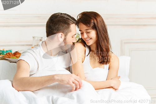 Image of Young adult heterosexual couple lying on bed in bedroom