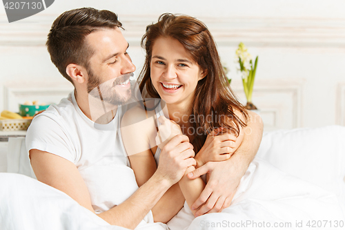 Image of Young adult heterosexual couple lying on bed in bedroom