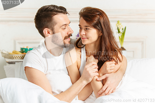 Image of Young adult heterosexual couple lying on bed in bedroom