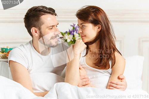 Image of Young adult heterosexual couple lying on bed in bedroom