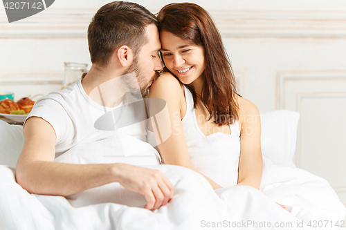 Image of Young adult heterosexual couple lying on bed in bedroom