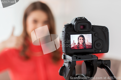 Image of woman with camera recording video at home