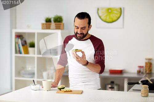 Image of man eating avocado sandwiches at home kitchen