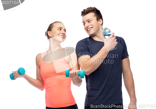 Image of sportive man and woman with dumbbell and water