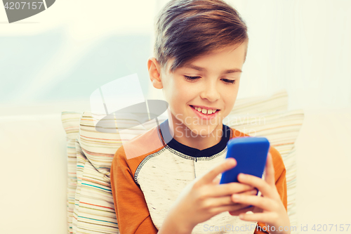 Image of boy with smartphone texting or playing at home