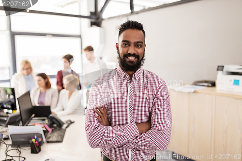 Image of happy indian man over creative team in office