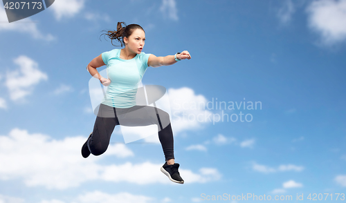 Image of sporty woman jumping in fighting pose over sky
