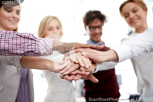 Image of happy business team with hands on top at office