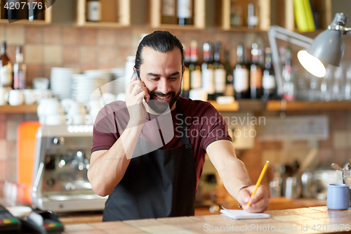 Image of happy man or waiter at bar calling on smartphone
