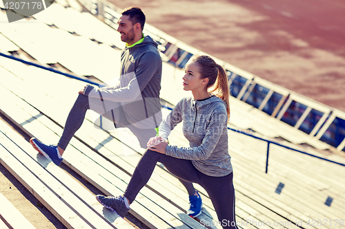 Image of couple stretching leg on stands of stadium