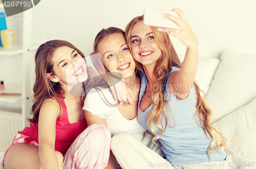 Image of teen girls with smartphone taking selfie at home