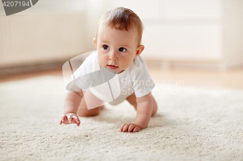 Image of little baby in diaper crawling on floor at home