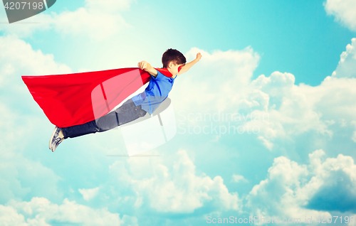 Image of boy in red superhero cape and mask flying over sky