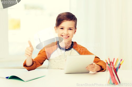 Image of happy boy with tablet pc showing thumbs up at home